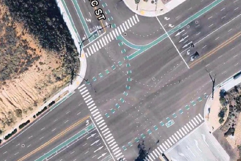 An overhead showing an 11-lane road with a slim unprotected bike lane running between traffic lanes