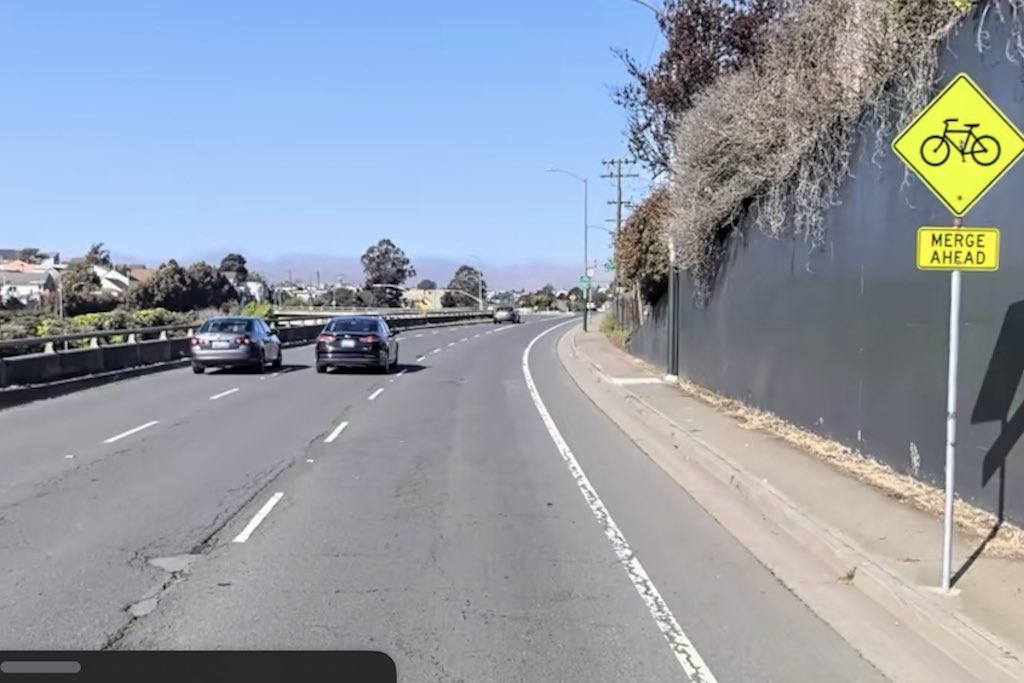 shows narrow unprotected bike lane running alongside three lanes of speeding highway traffic